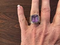 Ring on hand showing square purple stone in sterling silver setting