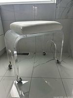 Full view of stool showing lucite base, casters, white seat