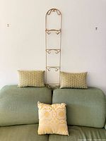 overall view: metal plate stand and three pillows on green sofa