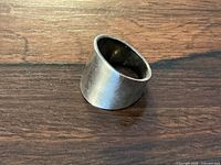 Wide sterling silver ring displayed on wooden surface