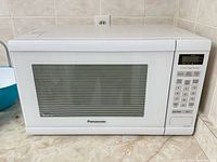 Front and side view of white Panasonic microwave showing window, keypad and branding