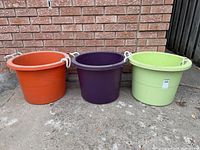Front view of three colored plastic tubs with rope handles aligned side by side