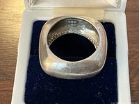 Inside view of ring in box showing 925 stamp and rounded square shape