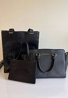 Group shot of three black designer handbags