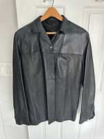 Front view of black leather shirt jacket on hanger