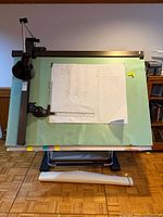 Full front view of drafting table showing work surface, frame, lamp, and straightedge