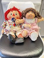 Both dolls seated together on chair showing overall appearance and scale