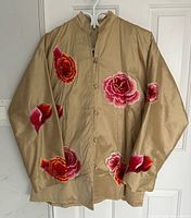 Full view of light gold silk jacket with red and fuchsia floral embroidery