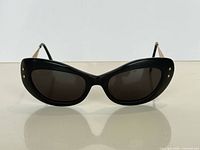 Front view of black cat-eye sunglasses with dark lenses and gold rivets