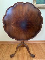 Front view of round burled walnut tilt-top table