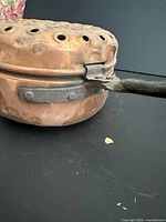 Side view showing copper body, iron handle and leather loop