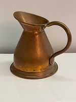 Full left side view of copper pitcher showing conical body, spout and handle
