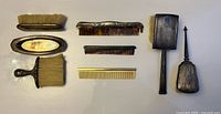 All eight items laid out: two hairbrushes, two clothes brushes, three combs, oval tray
