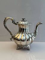 Full view of teapot showing melon body, spout, feet and lid