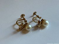 Pair of screw-back pearl earrings on flat surface