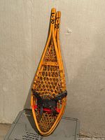 Full view of pair of wooden snowshoes leaning against wall