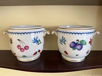 Front view of both Richard Ginori porcelain cachepots showing fruit and floral decoration