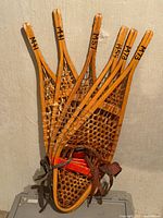 Stacked three pairs vintage wood snowshoes leaning against wall