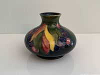 Front view of squat Moorcroft vase showing Leaf & Berry decoration