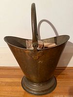 Full view of brass coal scuttle showing handle, body, pedestal base