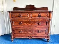 Front view showing all four drawers, knobs, carved trim and feet