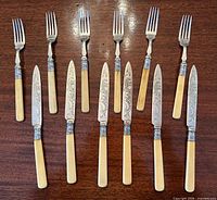 Full view showing 6 knives and 5 forks arranged on table