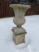 Complete urn atop pedestal standing in snow