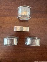 Front view of all four napkin rings showing shapes and engravings