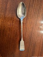 Full view of sterling silver basting spoon on wooden surface