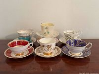 Group of six teacup and saucer sets showing pattern variety