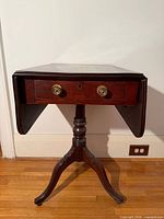 Front view showing drawer, brass pulls, pedestal base, leaves down