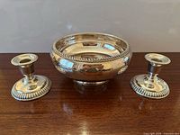 Front view of silver-plated pedestal bowl flanked by two matching candle holders
