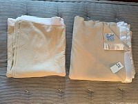 Two folded cream wool blankets on striped surface