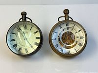 Front view of both glass and brass orb clocks