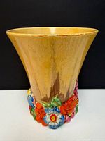 Full view of flared yellow pottery vase with colourful raised flowers at base