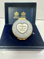 Lid design showing "A Token of Love" text and floral pattern inside presentation box