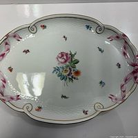 Top view of oval Herend porcelain tray showing floral décor, pink ribbon border and gold trim