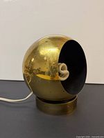 Side view of brass eyeball lamp on base