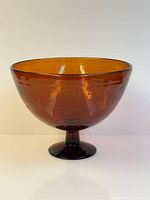 Side view of amber bubble glass pedestal bowl