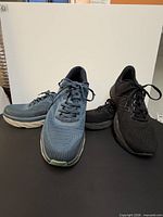 Blue Hoka Bondi 7 shoe and black New Balance shoe side by side on tabletop