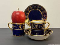 Front view of two cups and two saucers showing cobalt blue glaze and gilt pattern
