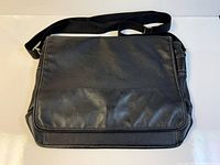 Front view of Roots black leather messenger bag with flap closed