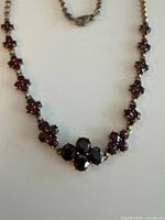 Front view showing garnet floral clusters and chain.