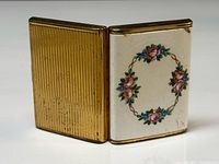 Case standing open showing ribbed gold back and floral enamel front