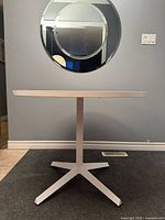 Full view of round white laminate X-base table