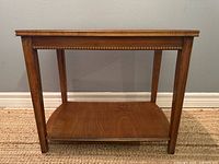 Full view of wooden end table showing top, legs, and lower shelf