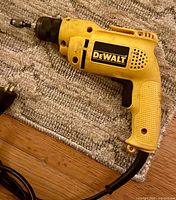 Left-side view of DeWalt corded drill on rug