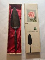 Pie server in red satin-lined box beside printed lid