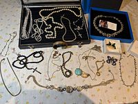 overview of all jewelry spread out including pearls, RFM necklace, brooches, chains, bracelet, wood box