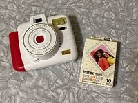 Front view of FAO Schwarz instant camera beside Fujifilm Instax Mini Sprinkles Bonbons film pack